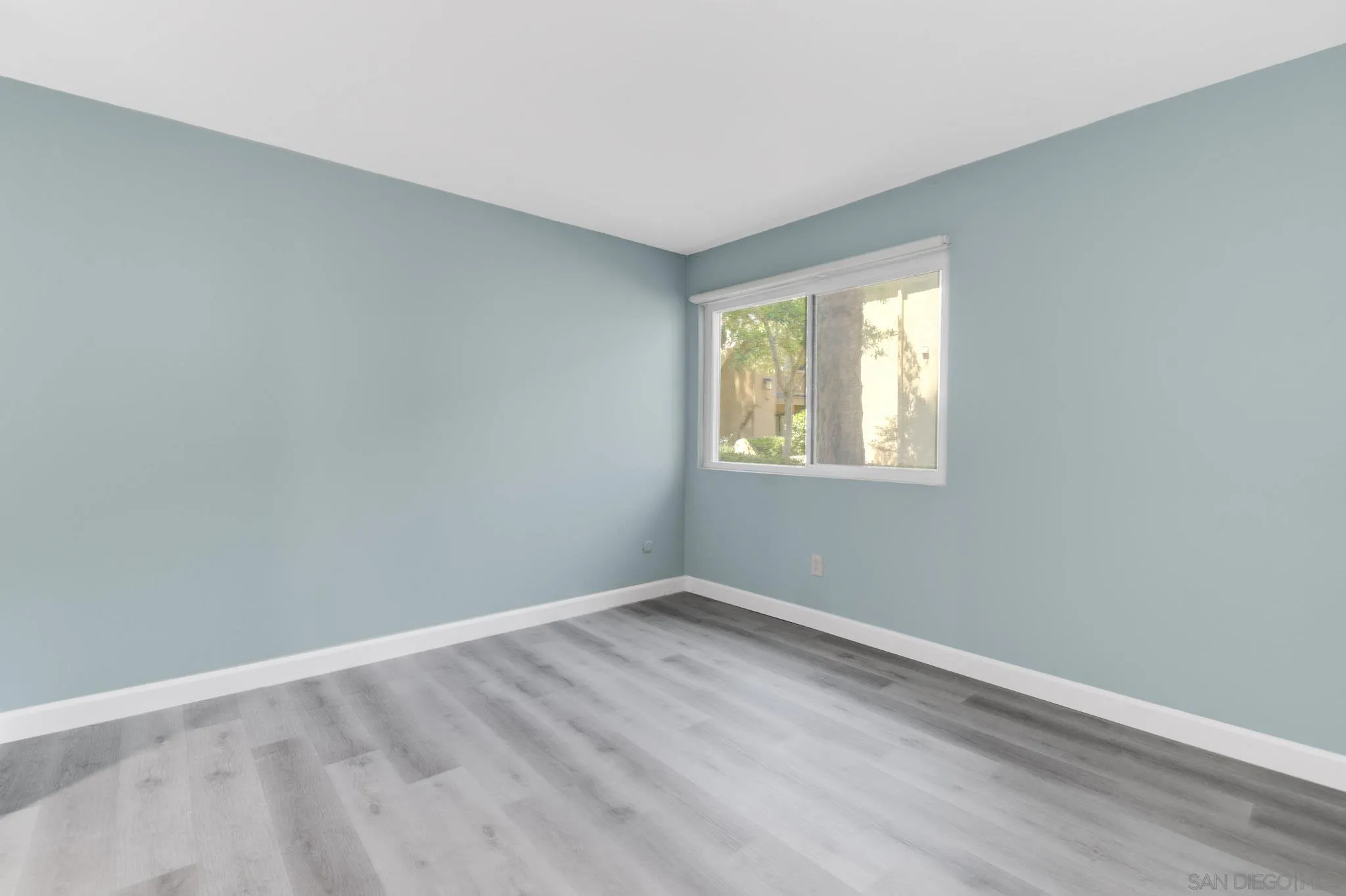 10222 Black Mountain Road, Unit 69 San Diego, CA 92126 - Photo 10 of 23 a view of an empty room with wooden floor and a window