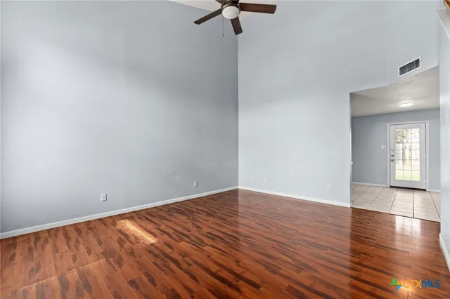 a view of empty room with wooden floor and fan