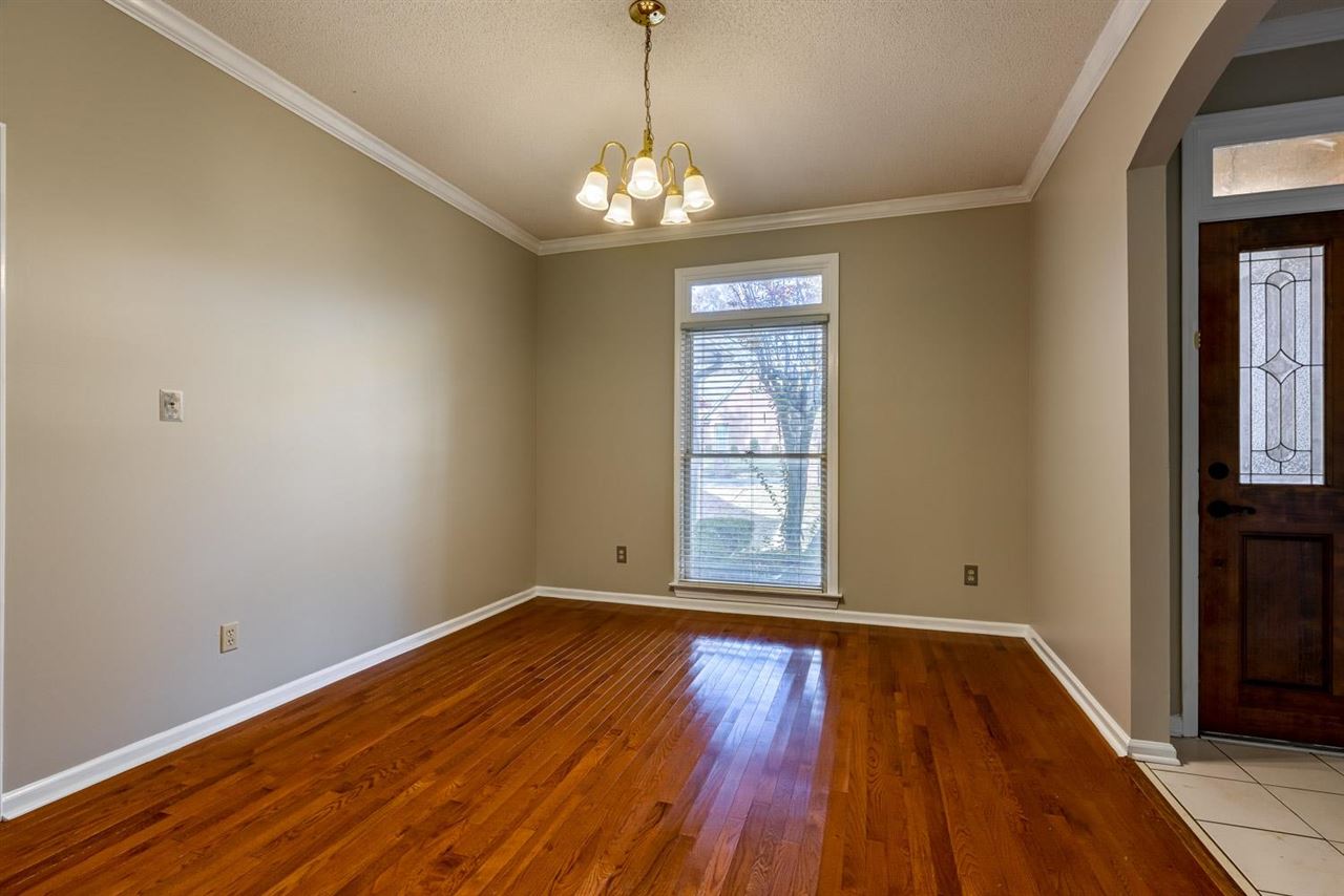 8779 Raspberry Lane Memphis, TN 38016 - Photo 6 of 25 a view of an empty room with wooden floor and a window