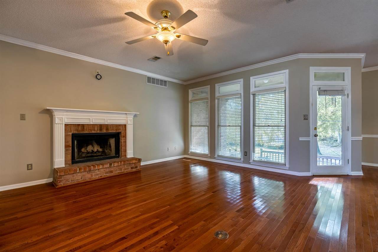 8779 Raspberry Lane Memphis, TN 38016 - Photo 7 of 25 a view of an empty room with wooden floor fireplace and a window