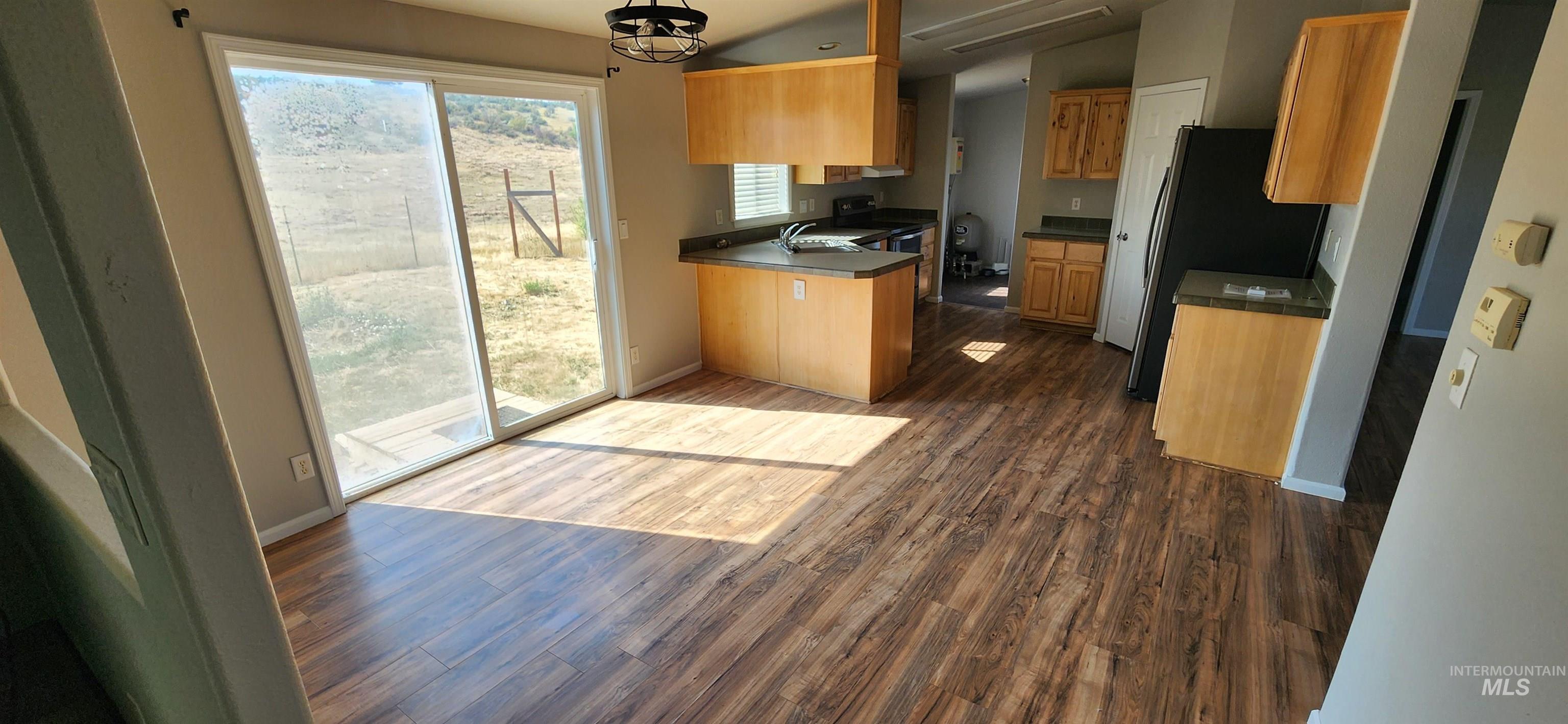 1817 South Exeter Road Council, ID 83612 - Photo 15 of 21 Kitchen with dark wood-style floors, hanging light fixtures, a peninsula, freestanding refrigerator, and dark countertops