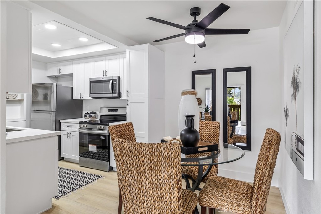 33852 Del Obispo Street, Unit 80 Dana Point, CA 92629 - Photo 10 of 36 a kitchen with stainless steel appliances kitchen island granite countertop a refrigerator a stove a sink a dining table and chairs with wooden floor