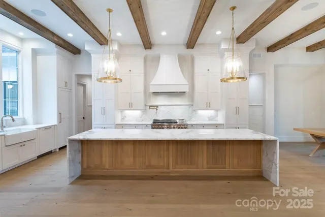 a view of large kitchen with granite countertop kitchen island white cabinets and stainless steel appliances