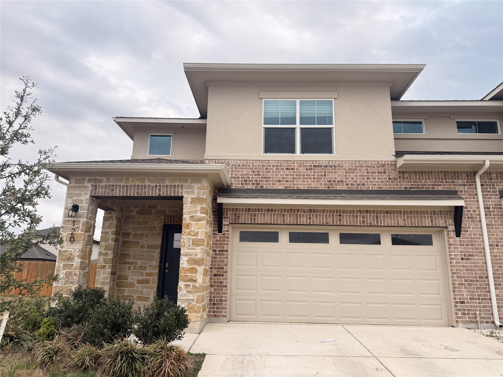 Prairie-style home with concrete driveway, a garage, stucco siding, and brick siding