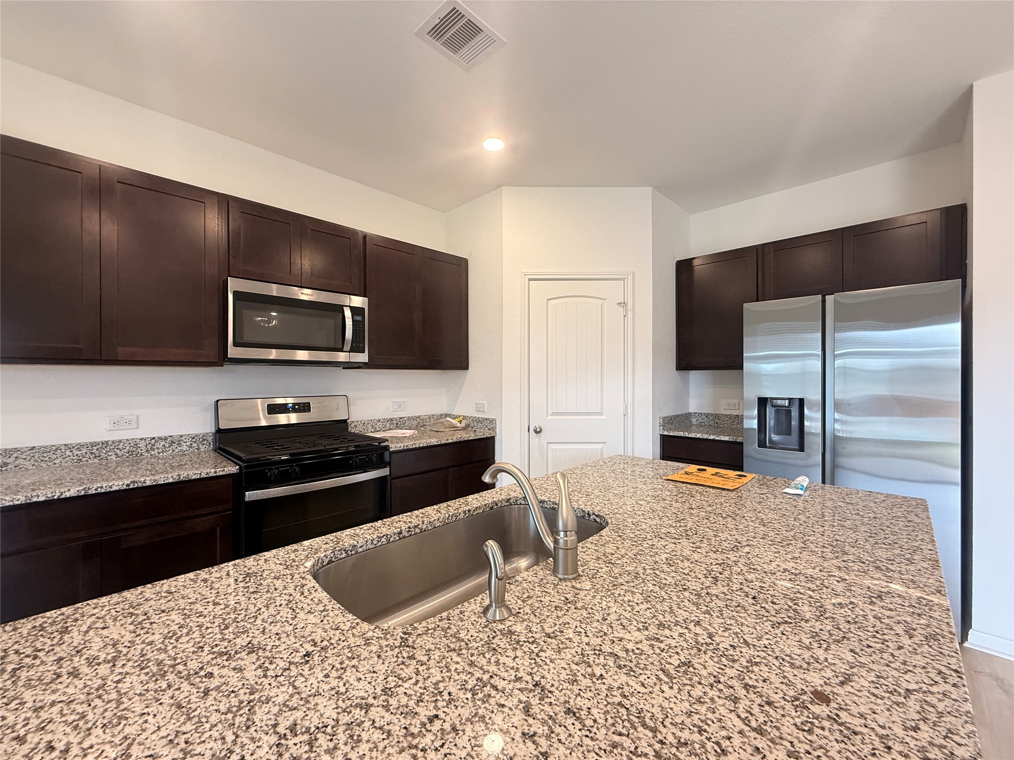 120 Calla Lane Georgetown, TX 78626 - Photo 3 of 19 Kitchen featuring stainless steel appliances, dark wood finish cabinetry, light stone counters, and recessed lighting