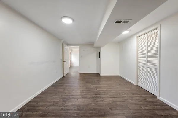 a view of an empty room with wooden floor and closet