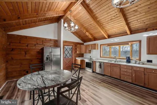 a kitchen with stainless steel appliances kitchen island granite countertop a table chairs and a wooden cabinets