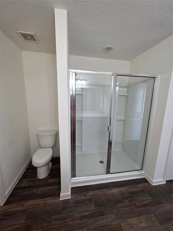 477 Bank Way Crowley, TX 76036 - Photo 11 of 39 Bathroom with a textured ceiling, wood finished floors, and a stall shower