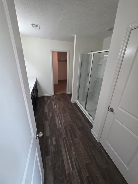 477 Bank Way Crowley, TX 76036 - Photo 26 of 39 Full bath featuring wood finished floors, a shower stall, vanity, a spacious closet, and a textured ceiling