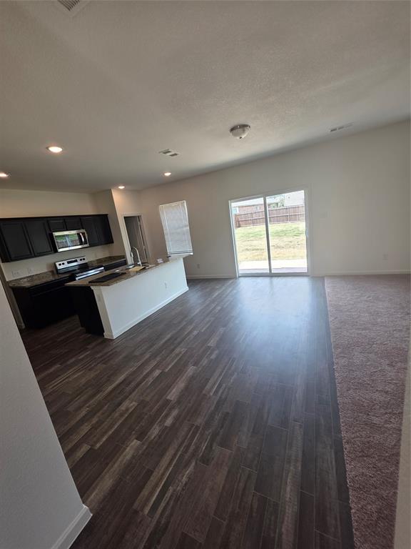 477 Bank Way Crowley, TX 76036 - Photo 38 of 39 Kitchen featuring open floor plan, plenty of natural light, dark cabinets, dark wood finished floors, and a textured ceiling