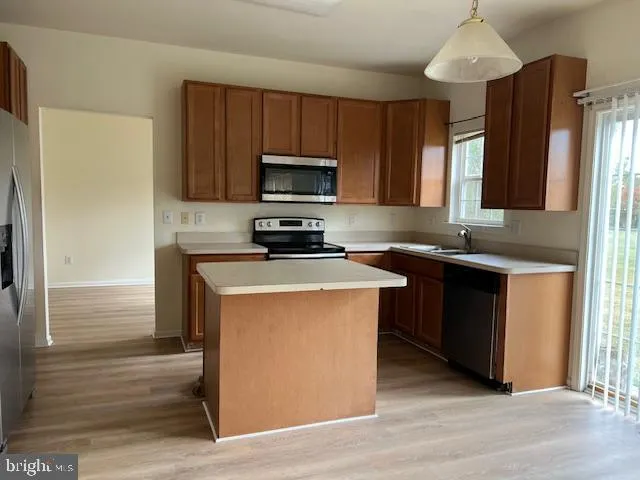 a kitchen with stainless steel appliances granite countertop a stove a sink dishwasher a refrigerator and a microwave oven with wooden floor