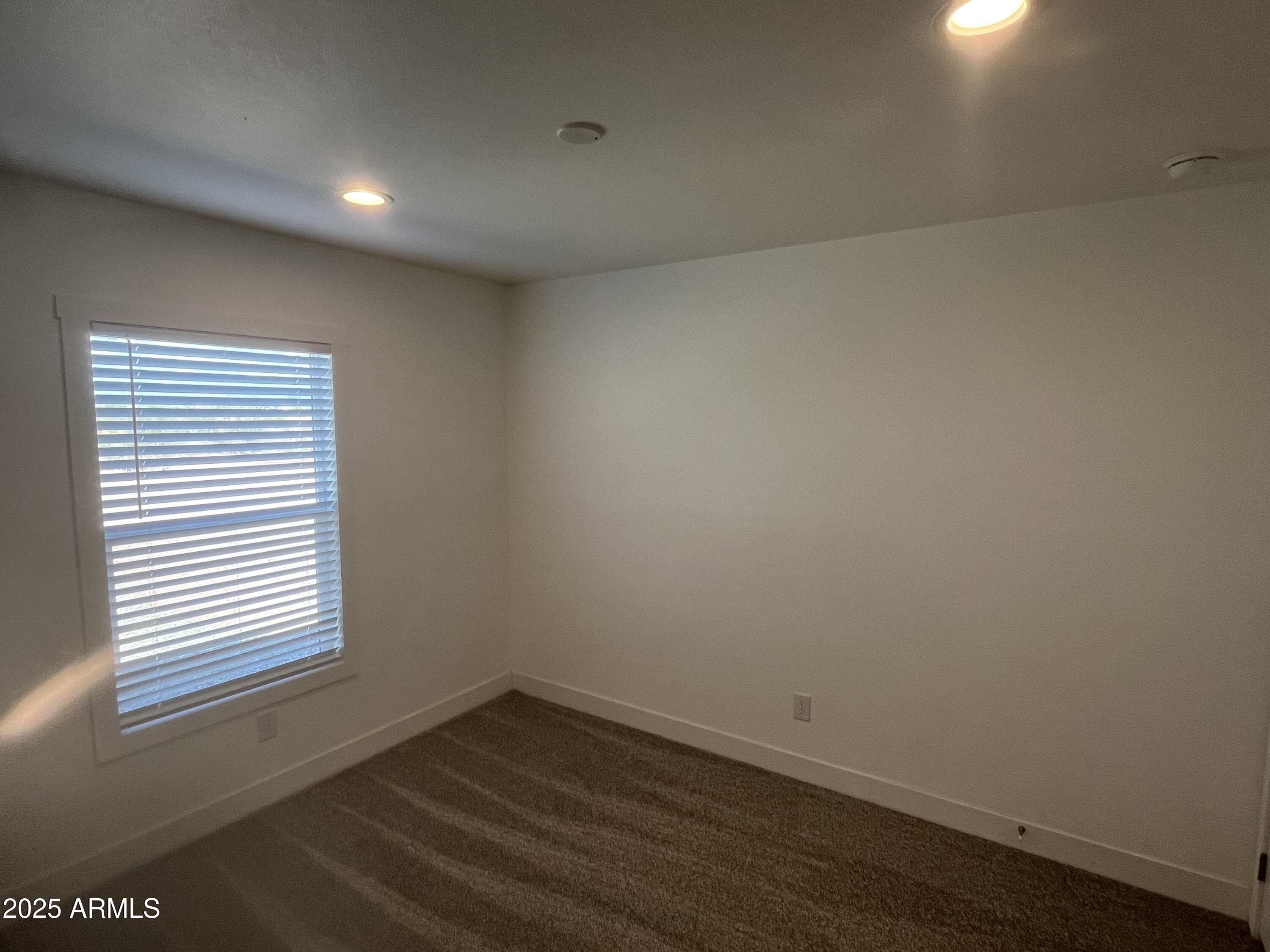 22936 West Forest Pleasant Place, Unit 2 Wittmann, AZ 85361 - Photo 9 of 17 a view of an empty room with wooden floor and a window