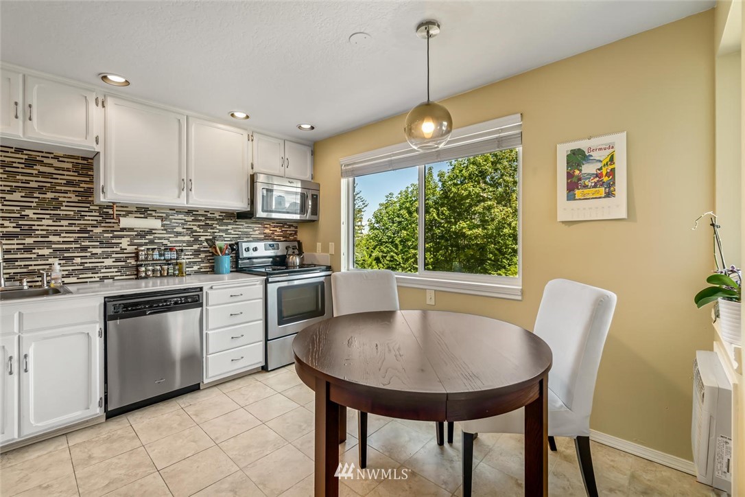 610 Aloha Street, Unit 302 Seattle, WA 98109 - Photo 12 of 27 a kitchen with stainless steel appliances granite countertop a sink a stove a kitchen island with chairs cabinets and couches