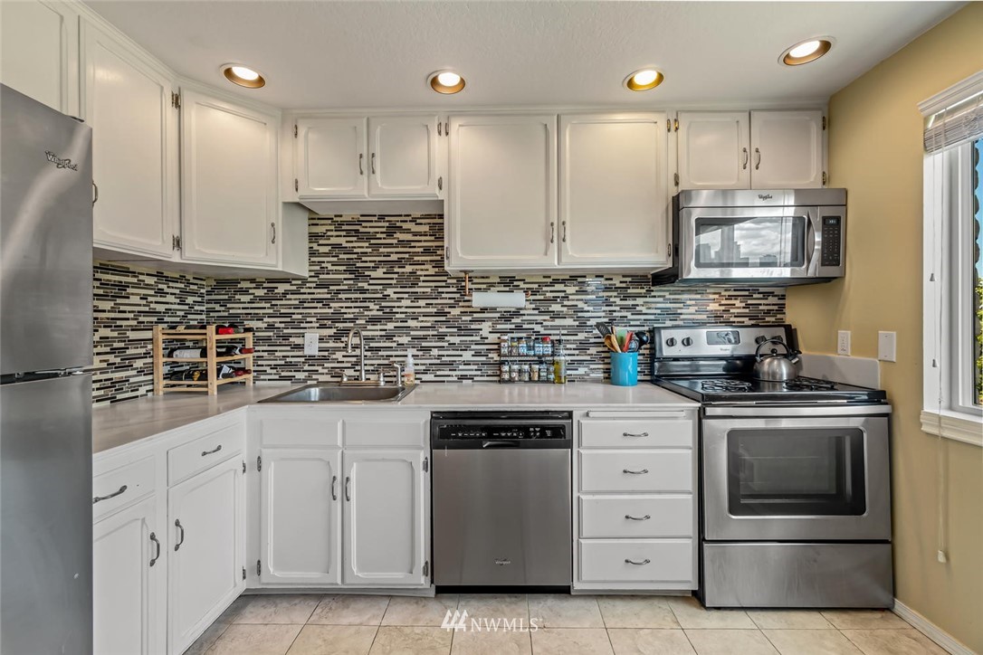 610 Aloha Street, Unit 302 Seattle, WA 98109 - Photo 10 of 27 a kitchen with white cabinets and stainless steel appliances