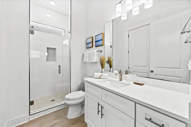a bathroom with a shower sink vanity mirror and toilet