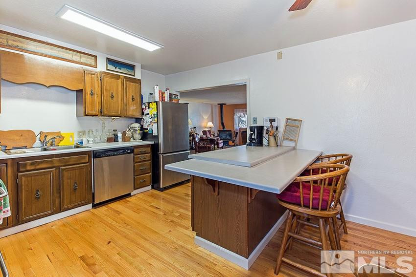 725 Reeves Avenue Reno, NV 89503 - Photo 7 of 15 a kitchen with stainless steel appliances kitchen island granite countertop a table chairs in it and wooden floors