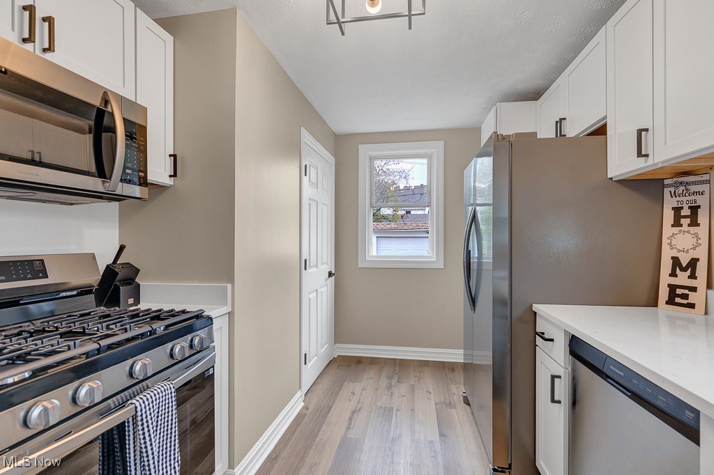 2127 Rossmoor Road Cleveland Heights, OH 44118 - Photo 21 of 21 Kitchen with white cabinetry, light countertops, baseboards, light wood-style floors, and appliances with stainless steel finishes
