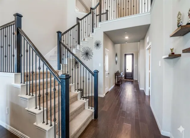 a view of staircase with lots of frames on wall and wooden floor
