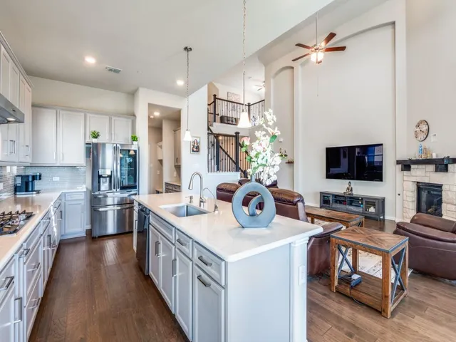 a kitchen with stainless steel appliances a stove a sink dishwasher a refrigerator and a stove with wooden floor