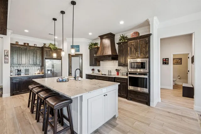 a kitchen with stainless steel appliances kitchen island granite countertop a stove a sink and a refrigerator