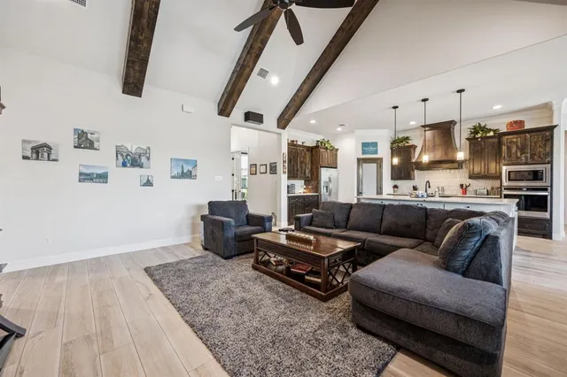 a living room with furniture kitchen view and a wooden floor