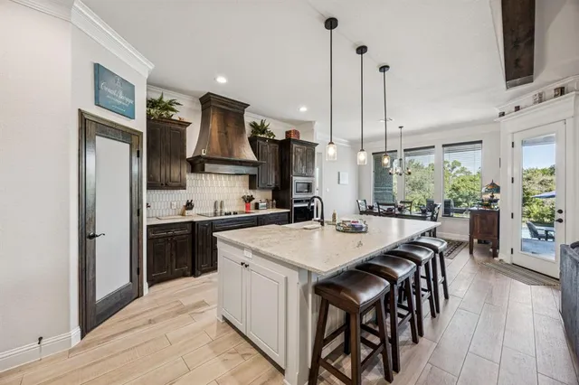 a kitchen with stainless steel appliances kitchen island granite countertop a stove a sink a refrigerator a dining table and chairs with wooden floor