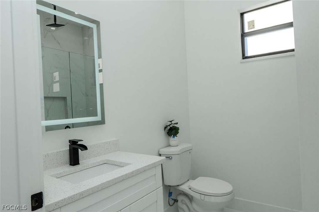 3206 14th Street Southwest Lehigh Acres, FL 33976 - Photo 16 of 38 a bathroom with a toilet sink and mirror