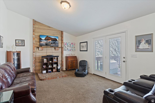 5321 South 3100th Street West Roy, UT 84067 - Photo 29 of 64 Spacious living area featuring a vaulted ceiling and a brick-accented wall with a fireplace hearth