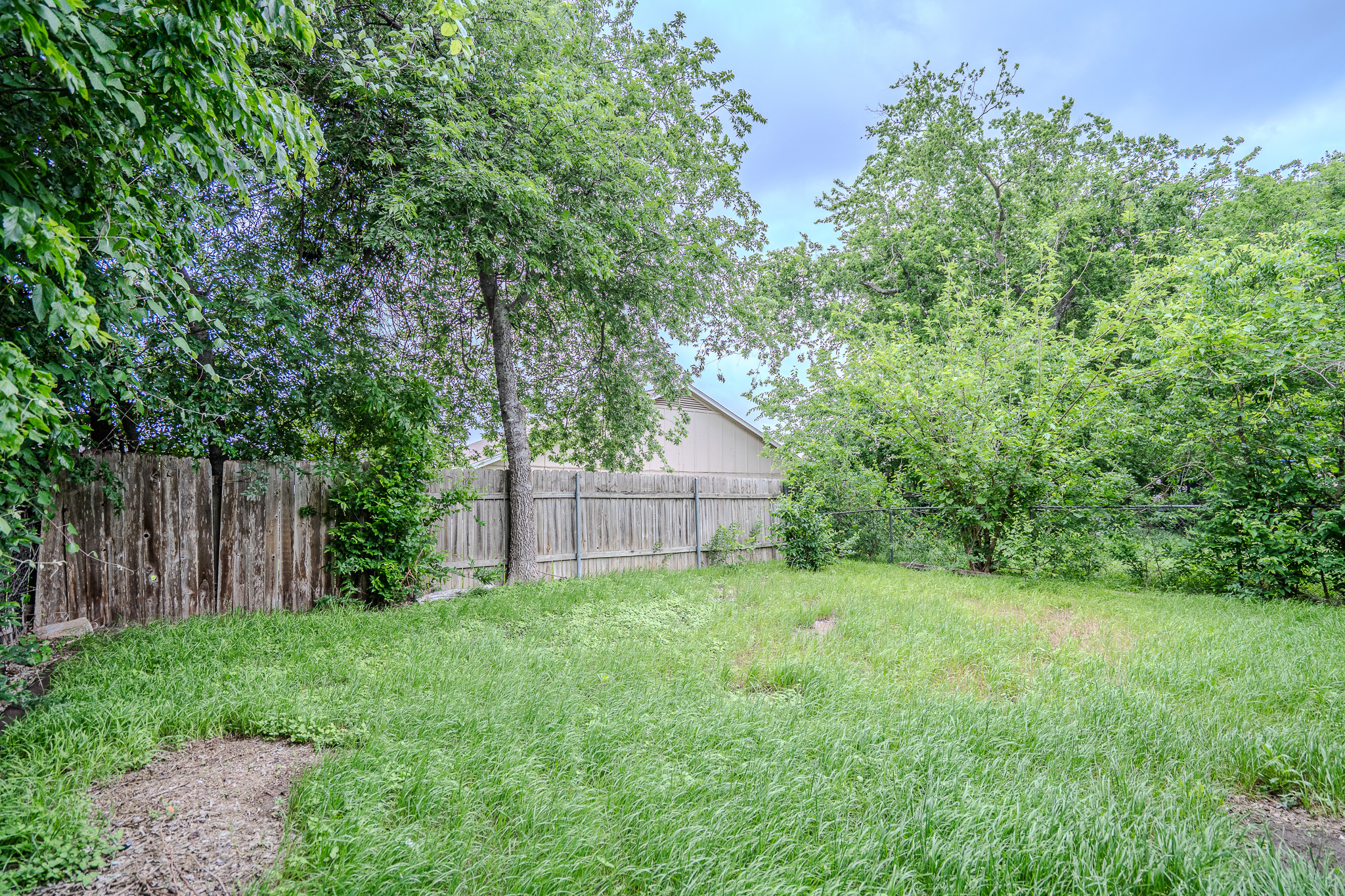 12403 Tree Line Drive, Unit B Austin, TX 78729 - Photo 15 of 16 a view of a backyard with a small cabin and wooden fence