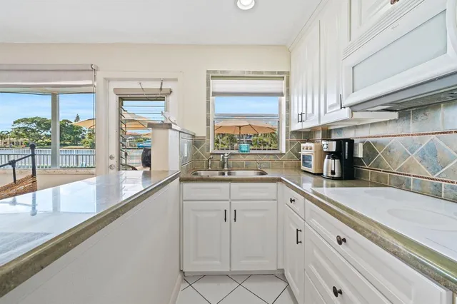 a kitchen with white cabinets and a window