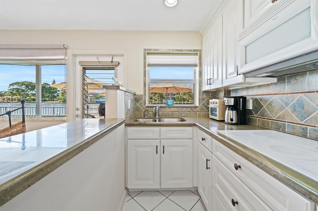 701 South Riverside Drive, Unit 107 Pompano Beach, FL 33062 - Photo 14 of 27 a kitchen with white cabinets and a window
