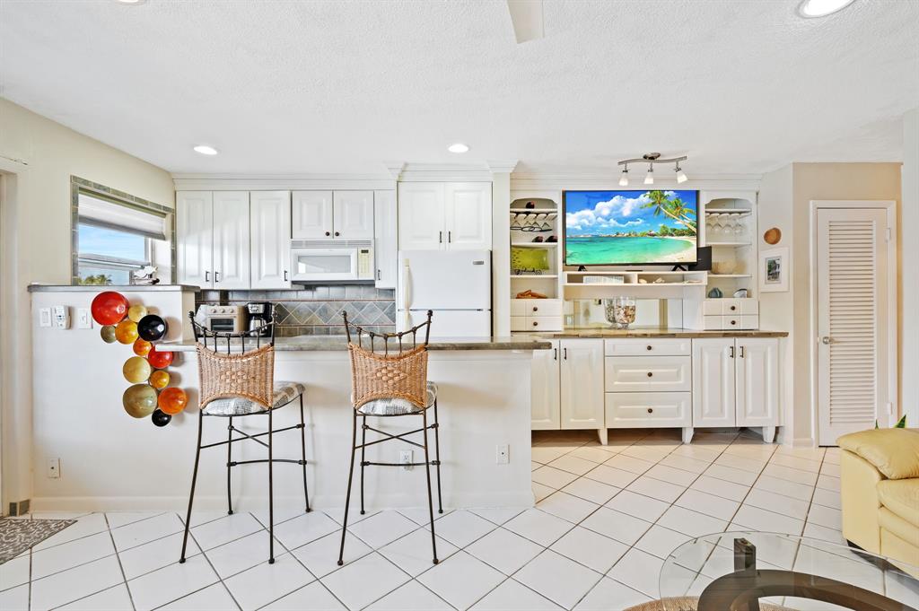 701 South Riverside Drive, Unit 107 Pompano Beach, FL 33062 - Photo 9 of 27 a living room with furniture a flat screen tv and kitchen view