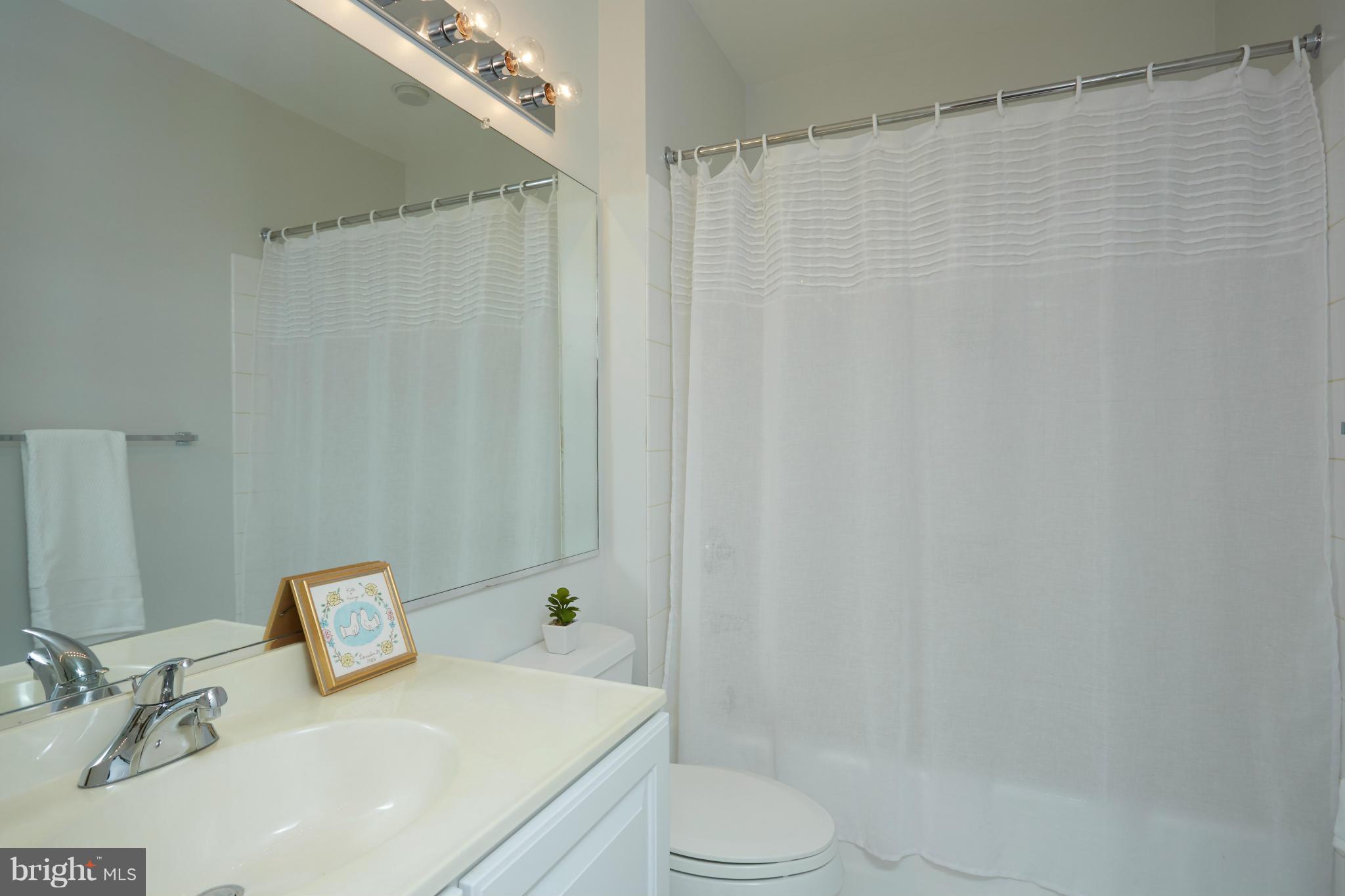 7447 Arlington Road Bethesda, MD 20814 - Photo 17 of 20 a bathroom with a sink a toilet and shower curtain