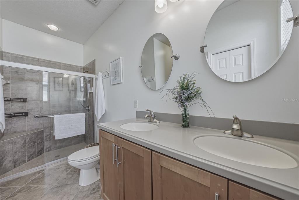 4489 Strathmore Drive Lake Wales, FL 33859 - Photo 36 of 89 a bathroom with a toilet a sink a mirror and a shower