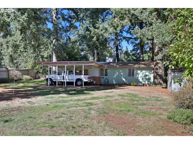 a view of a yard with large trees and a barn
