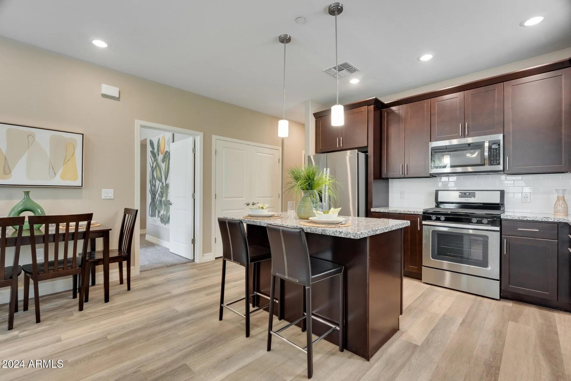 1350 South Ellsworth Road, Unit 2A Mesa, AZ 85209 - Photo 7 of 49 a kitchen with stainless steel appliances granite countertop a stove a refrigerator a kitchen island a dining table and chairs