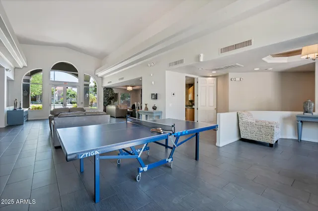 a living room with couches a table and potted plants with wooden floor