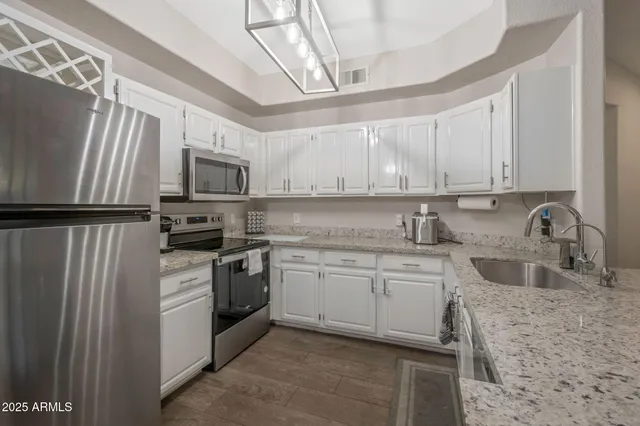 a kitchen with stainless steel appliances granite countertop a sink stove microwave and refrigerator