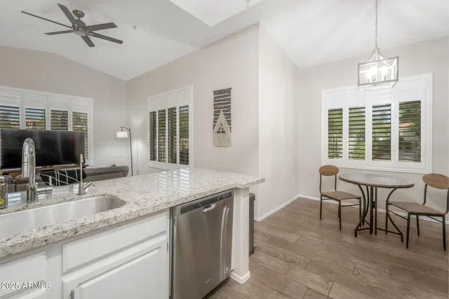 a dining hall with stainless steel appliances granite countertop a sink dishwasher a dining table and chairs with wooden floor