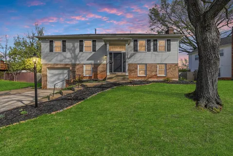 a front view of a house with a yard and trees