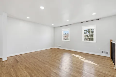 an empty room with wooden floor and a ceiling fan