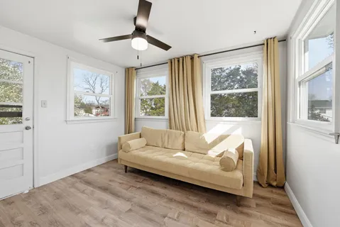 a view of an empty room with wooden floor and a ceiling fan