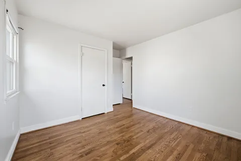 a view of empty room with wooden floor and window