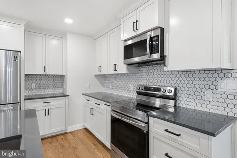 a kitchen with stainless steel appliances kitchen island granite countertop a refrigerator a stove a sink dishwasher and a refrigerator with wooden floor