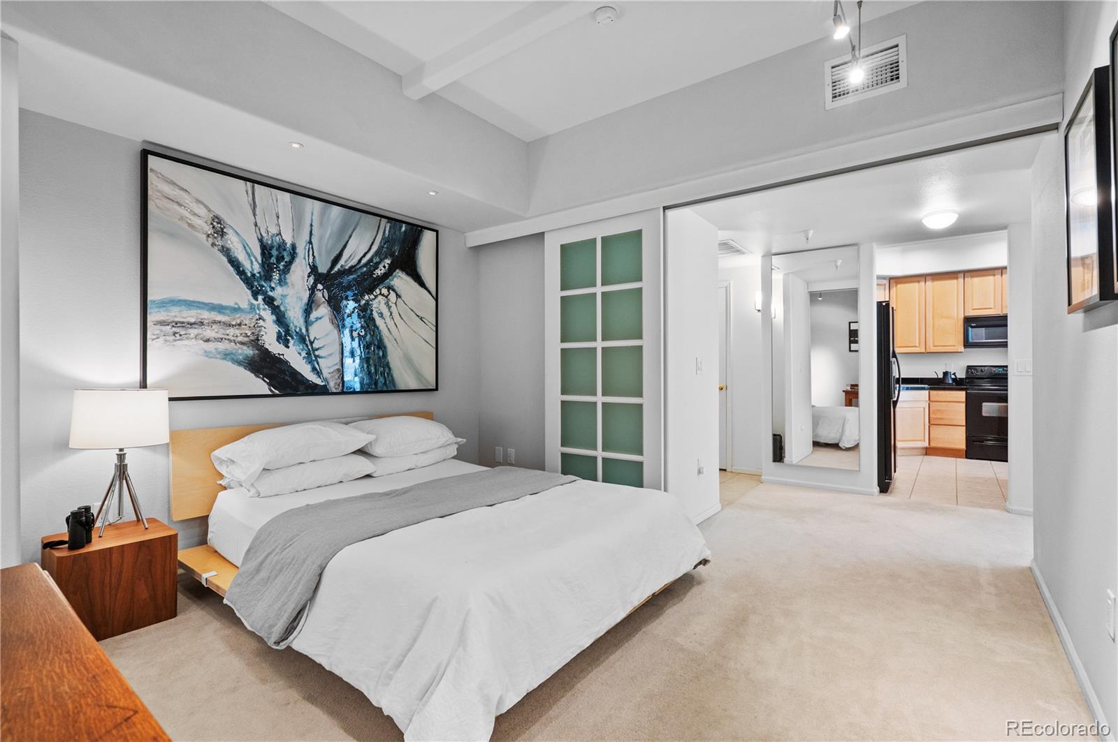 180 Cook Street, Unit 203 Denver, CO 80206 - Photo 26 of 44 a bedroom with a large bed and a painting on the wall