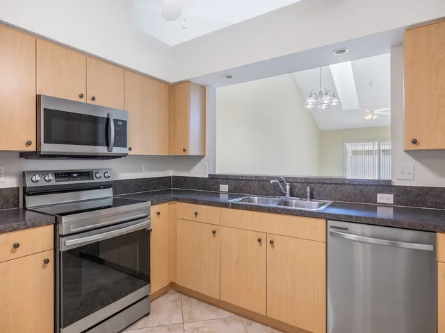 a kitchen with granite countertop a sink stove and microwave