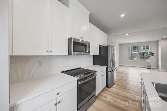 a kitchen with granite countertop white cabinets and stainless steel appliances