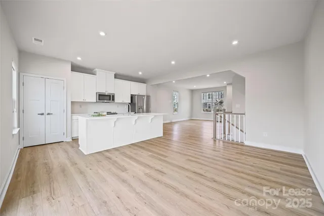 a view of a kitchen with kitchen island a sink wooden floor and white stainless steel appliances