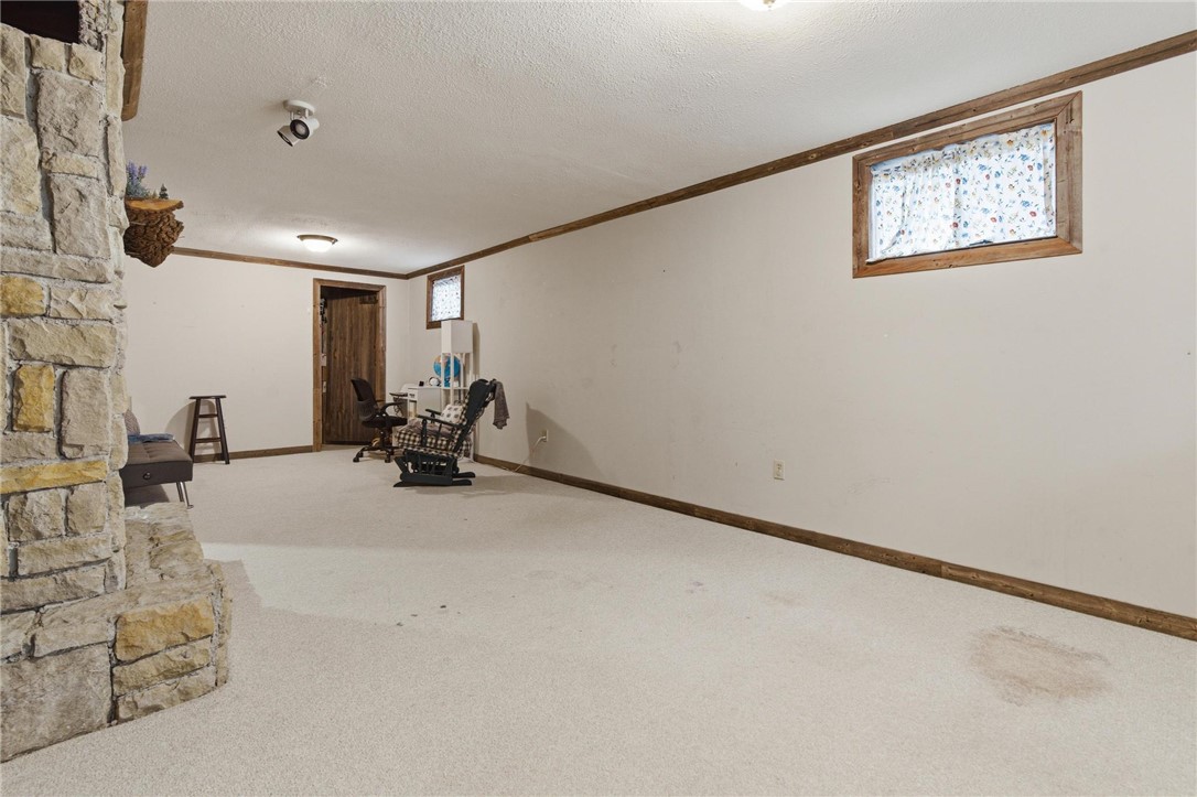 8747 Waynes Way Blanchester, OH 45107 - Photo 21 of 40 This expansive basement offers versatile living space with a charming stone fireplace and carpet flooring.
