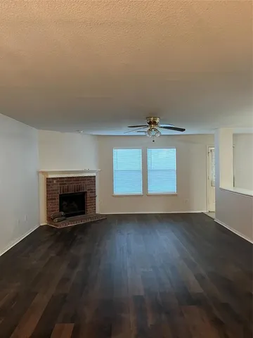 an empty room with wooden floor fireplace and windows